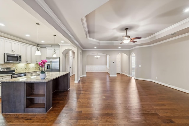 kitchen with arched walkways, stainless steel appliances, visible vents, open shelves, and a tray ceiling