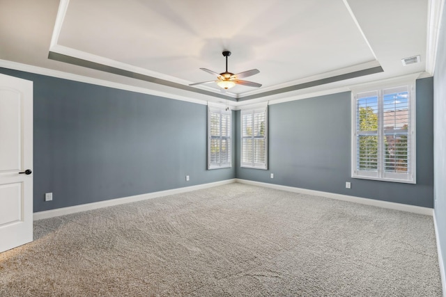 unfurnished room with crown molding, a tray ceiling, carpet, and baseboards