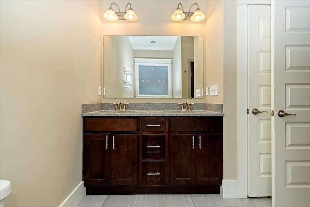 full bathroom featuring a sink, baseboards, and double vanity