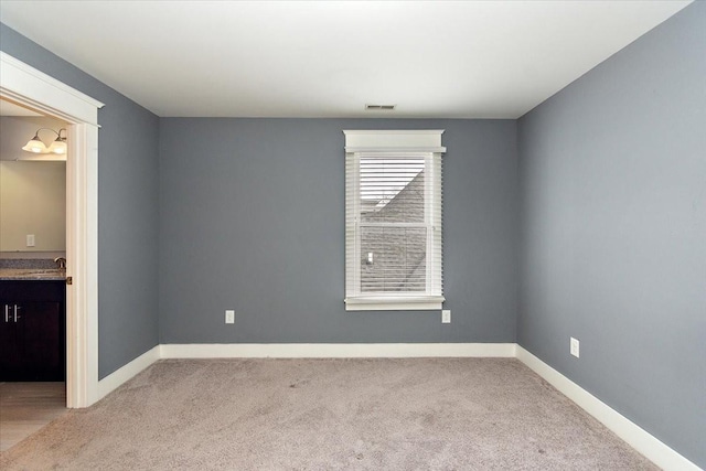 empty room featuring a sink, baseboards, visible vents, and carpet flooring