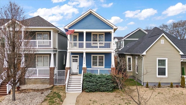 view of front of home with stairs, a porch, a shingled roof, and a balcony