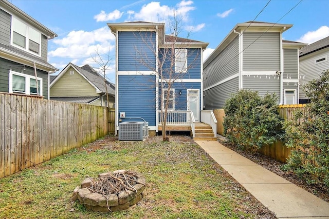 rear view of house with a fire pit, central AC, a fenced backyard, and a wooden deck