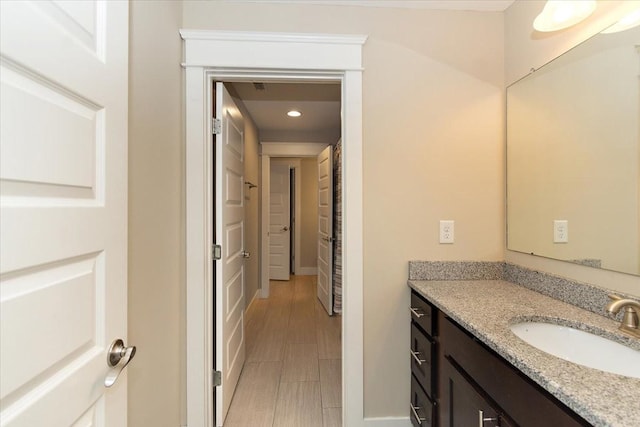 bathroom with baseboards, wood tiled floor, vanity, and recessed lighting