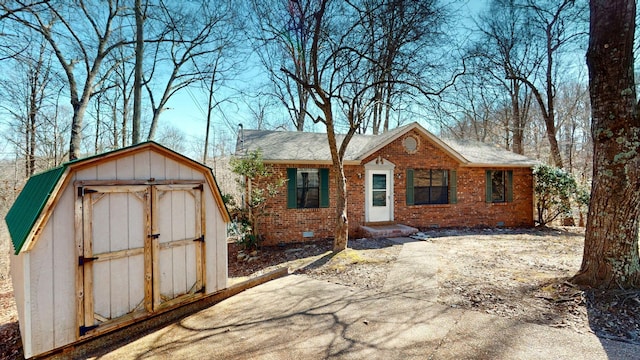 view of front of house with an outbuilding, crawl space, brick siding, and a storage unit