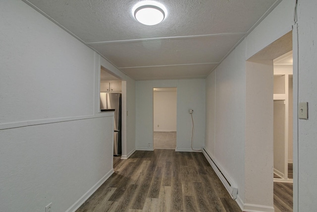 hall with dark wood-style floors, a baseboard heating unit, and a textured ceiling