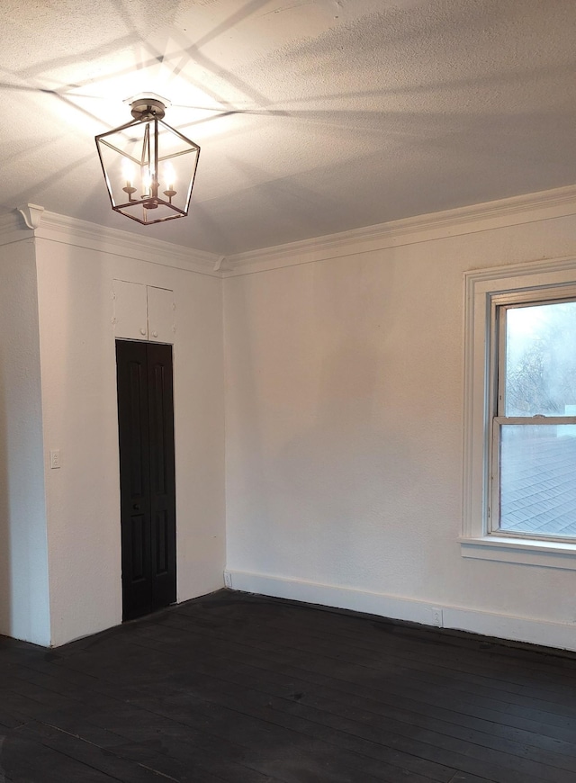 spare room featuring baseboards, ornamental molding, dark wood-style flooring, and a notable chandelier