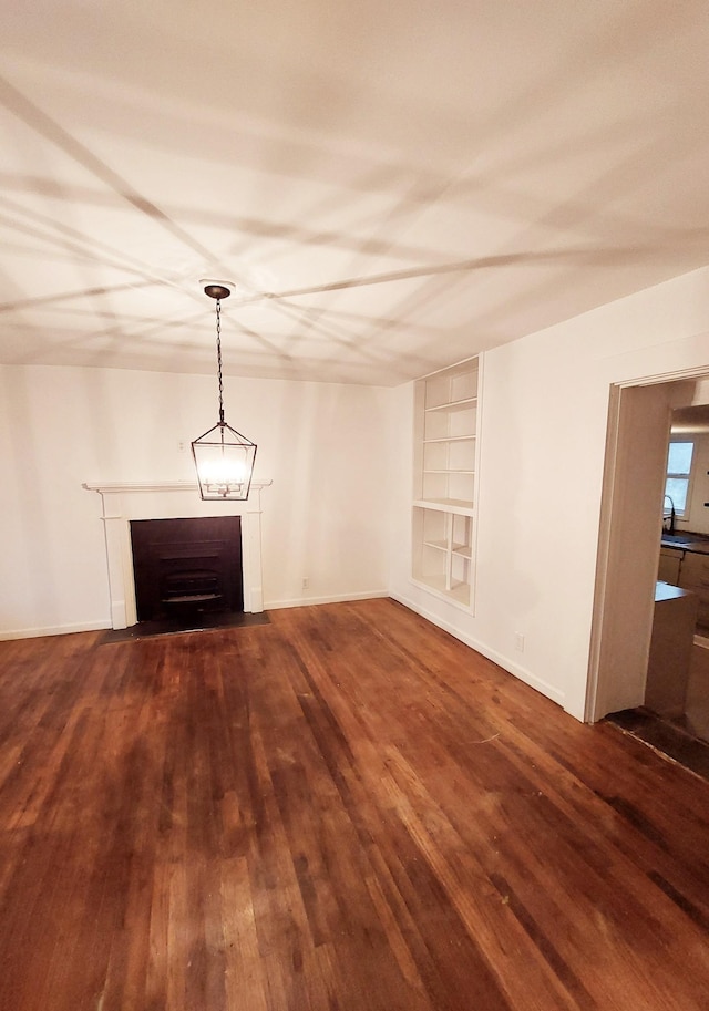 unfurnished living room with wood finished floors, a sink, baseboards, a fireplace with flush hearth, and built in features