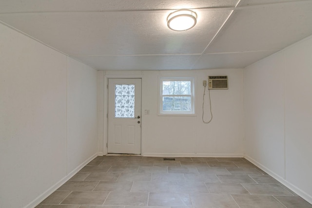 basement featuring baseboards, a textured ceiling, and a wall mounted air conditioner