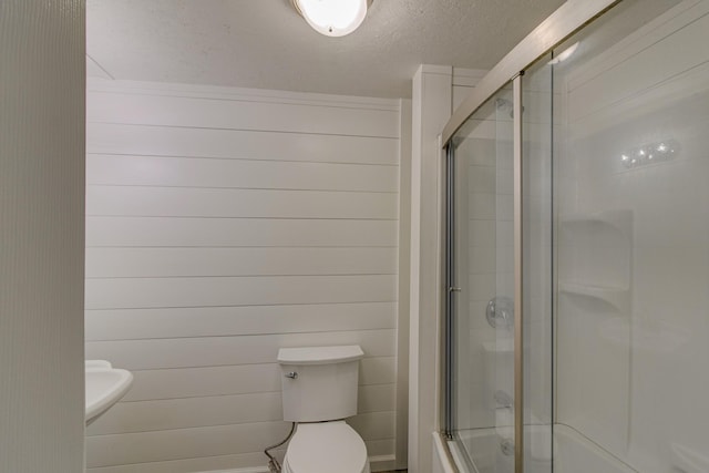 full bath featuring shower / bath combination with glass door, a textured ceiling, and toilet