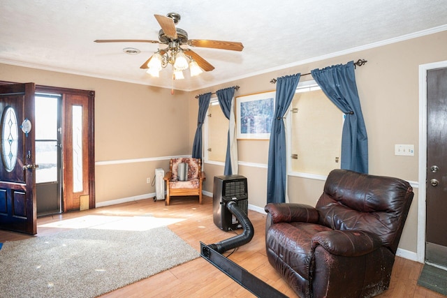 sitting room with a wealth of natural light, crown molding, baseboards, and wood finished floors