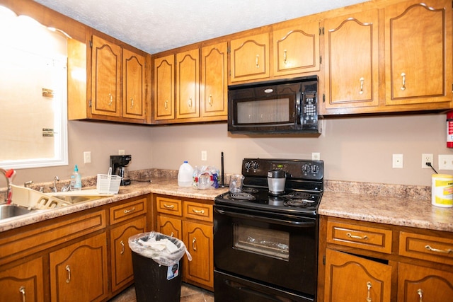 kitchen with brown cabinetry, light countertops, a textured ceiling, and black appliances