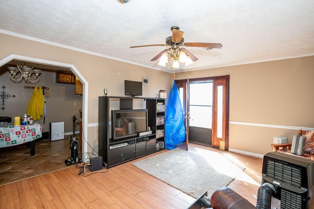 living room featuring baseboards, wood finished floors, a ceiling fan, and crown molding