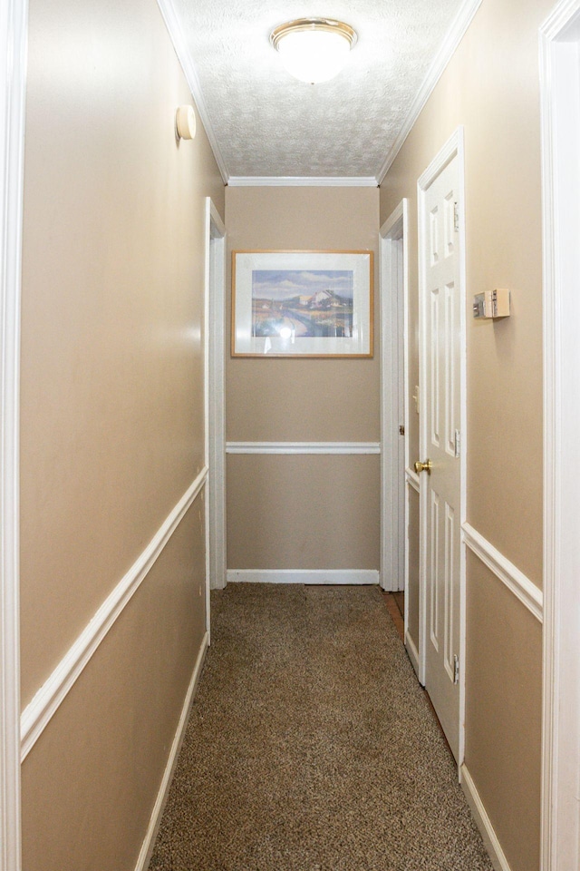 hall featuring carpet floors, ornamental molding, a textured ceiling, and baseboards