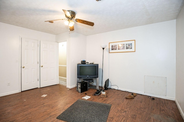 interior space featuring ceiling fan, a textured ceiling, wood finished floors, and baseboards