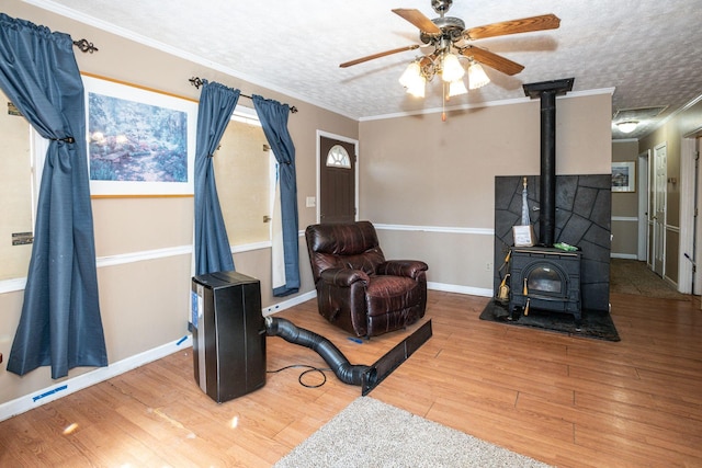 living room featuring a textured ceiling, wood finished floors, a wood stove, and crown molding