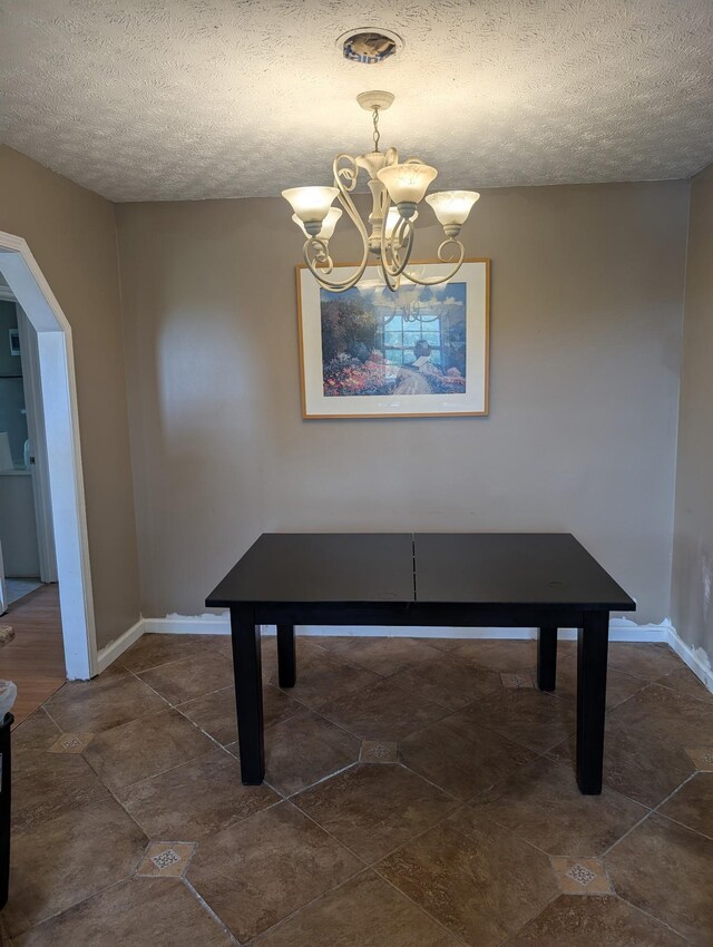 4460 Bold Springs Rd, Mc Ewen, TN 37101 - unfurnished dining area with a textured ceiling, a chandelier, arched walkways, and baseboards