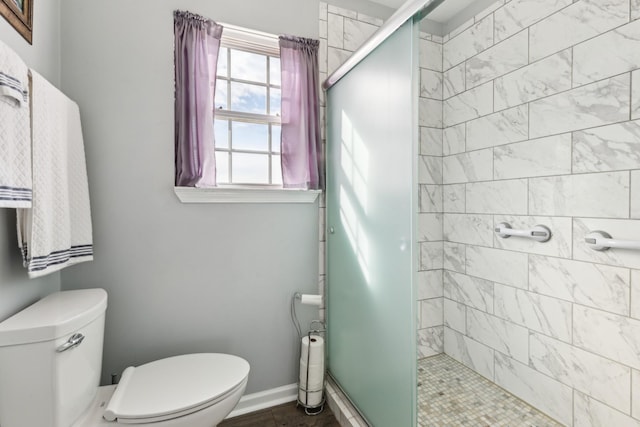 full bathroom with baseboards, a shower stall, and toilet