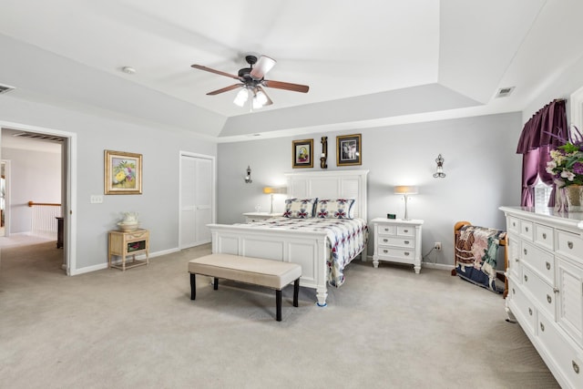 bedroom featuring a tray ceiling, light colored carpet, visible vents, and baseboards