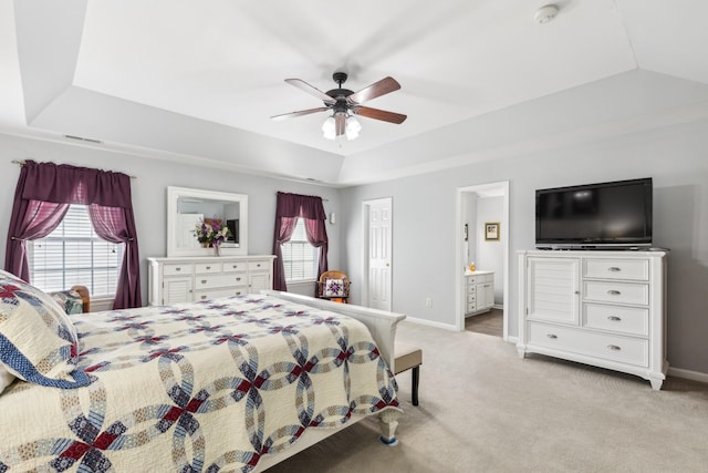 bedroom with light colored carpet, a tray ceiling, and multiple windows