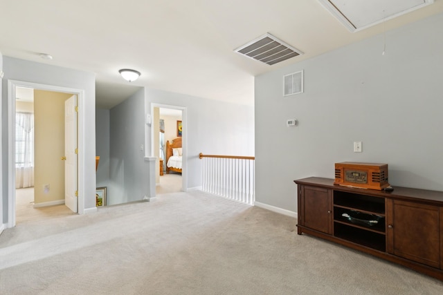 unfurnished room with attic access, visible vents, light carpet, and baseboards