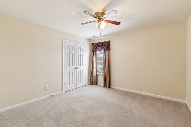 carpeted empty room featuring baseboards and a ceiling fan