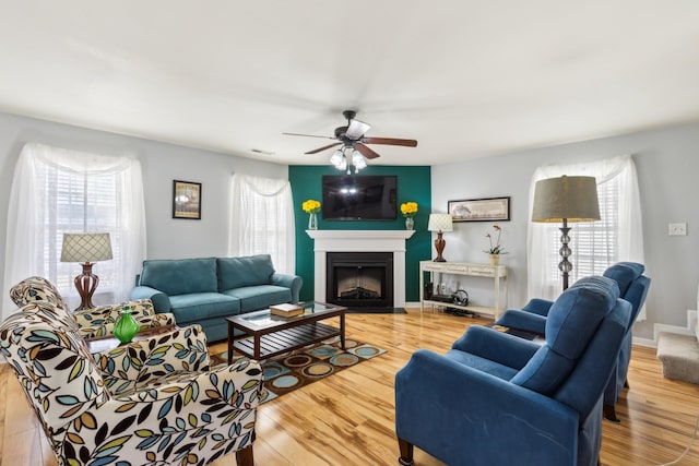 living area with a fireplace with flush hearth, wood finished floors, visible vents, and baseboards