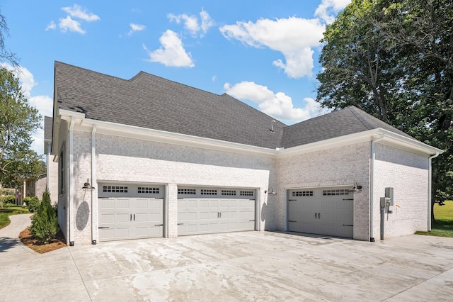 view of home's exterior with a garage, brick siding, driveway, and roof with shingles