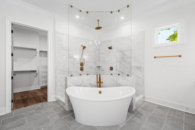 full bathroom featuring a soaking tub, a spacious closet, ornamental molding, baseboards, and walk in shower