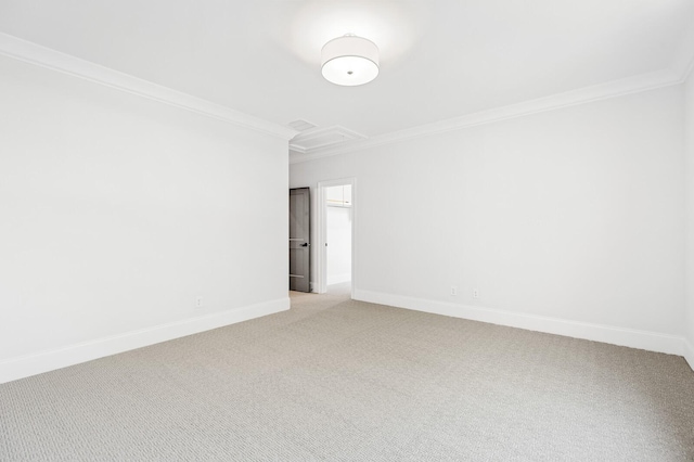 spare room with baseboards, ornamental molding, attic access, and light colored carpet