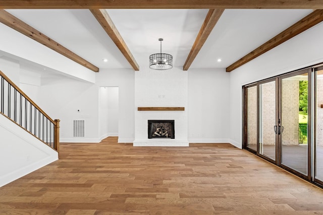 unfurnished living room featuring baseboards, visible vents, stairs, light wood-type flooring, and a brick fireplace