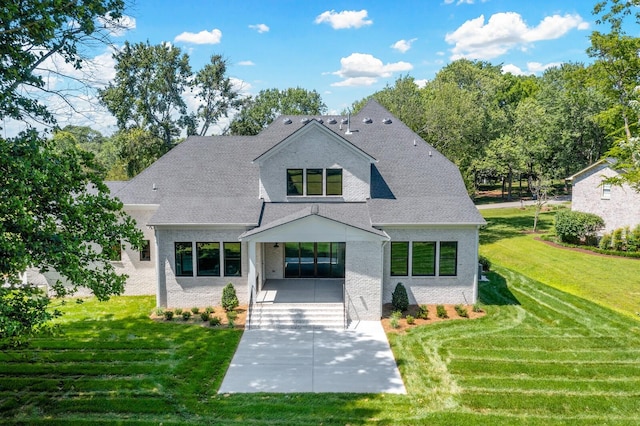 view of front of home with a shingled roof, a front yard, and brick siding