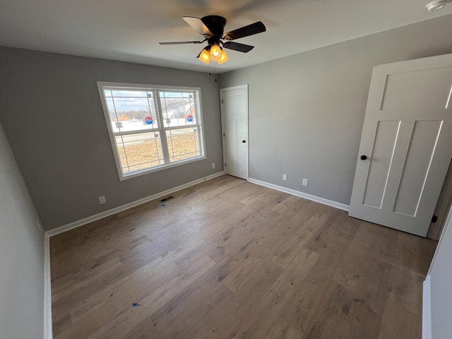 unfurnished bedroom featuring light wood finished floors, visible vents, baseboards, and a ceiling fan