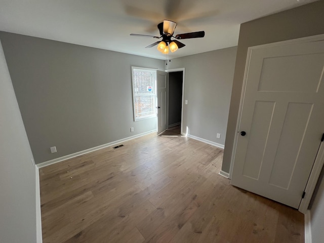 unfurnished bedroom featuring light wood-style flooring, visible vents, ceiling fan, and baseboards