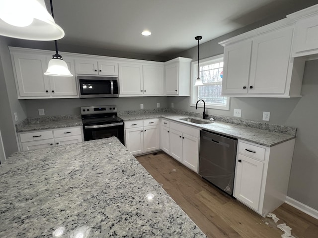 kitchen featuring dark wood-style flooring, appliances with stainless steel finishes, white cabinets, and a sink