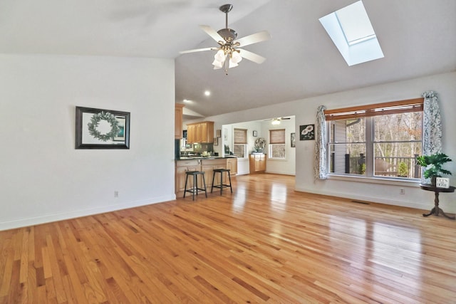 unfurnished living room featuring high vaulted ceiling, baseboards, ceiling fan, and light wood finished floors