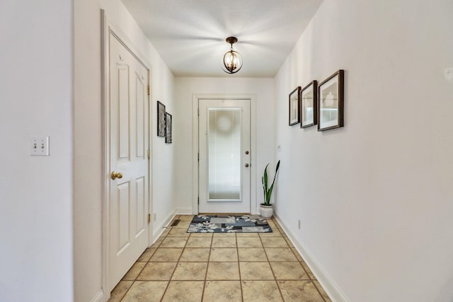 doorway with light tile patterned floors and baseboards