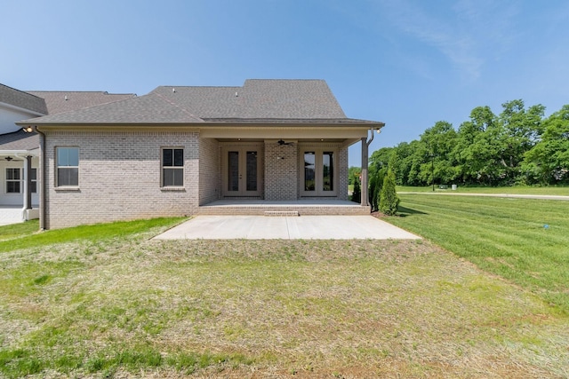 rear view of property with ceiling fan, brick siding, french doors, a lawn, and a patio area