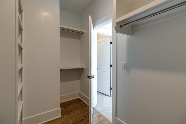 walk in closet with dark wood finished floors