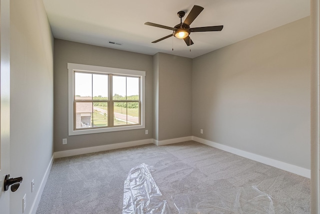 empty room featuring carpet floors, baseboards, visible vents, and a ceiling fan