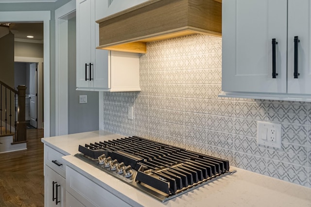 kitchen featuring tasteful backsplash, stainless steel gas cooktop, custom range hood, dark wood-type flooring, and white cabinetry