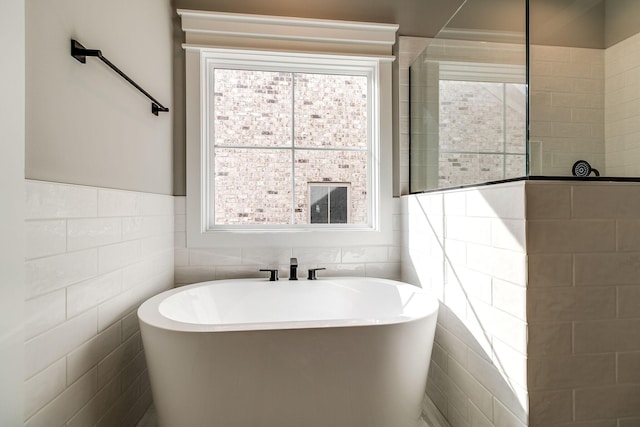 bathroom with a freestanding tub, plenty of natural light, and tile walls