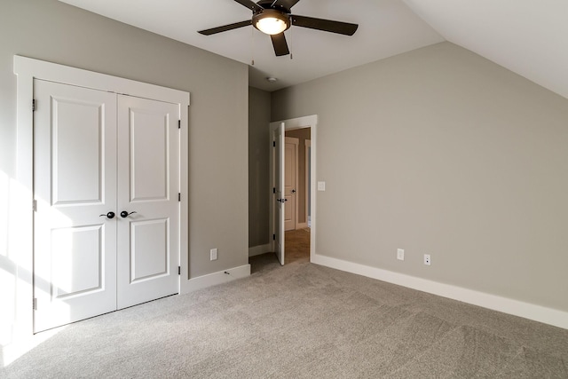 unfurnished bedroom featuring baseboards, a ceiling fan, carpet, vaulted ceiling, and a closet