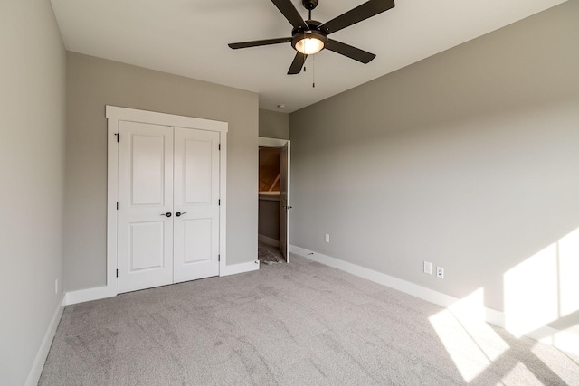 unfurnished bedroom with ceiling fan, a closet, baseboards, and carpet flooring