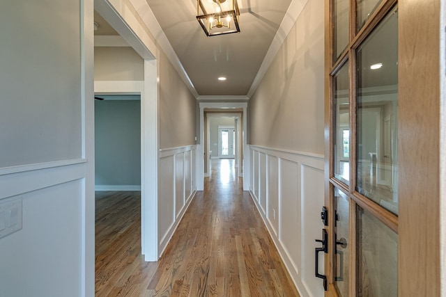 hall featuring crown molding, recessed lighting, a decorative wall, wainscoting, and wood finished floors