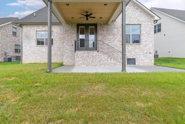 rear view of house with brick siding, a shingled roof, a lawn, a ceiling fan, and cooling unit