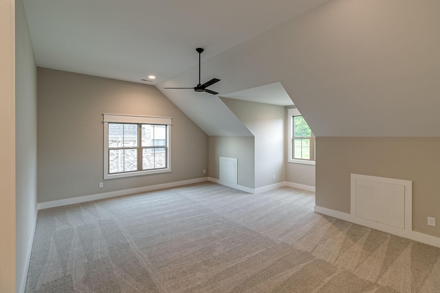 additional living space with light carpet, vaulted ceiling, a ceiling fan, and baseboards