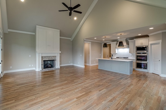 unfurnished living room with crown molding, light wood-style floors, a fireplace, and baseboards