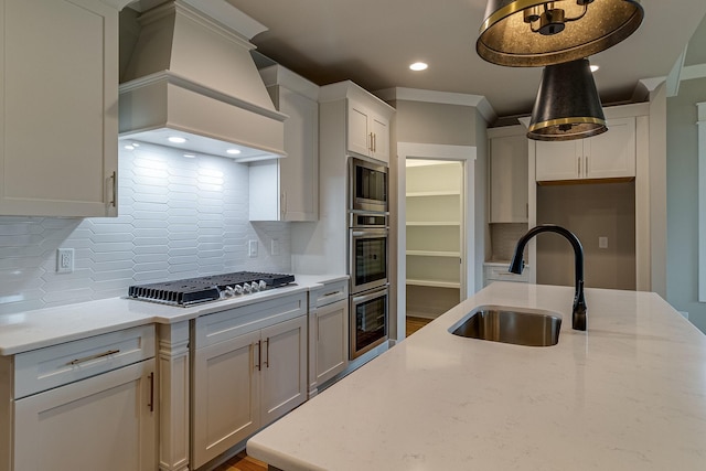 kitchen with stainless steel appliances, a sink, backsplash, custom exhaust hood, and light stone countertops