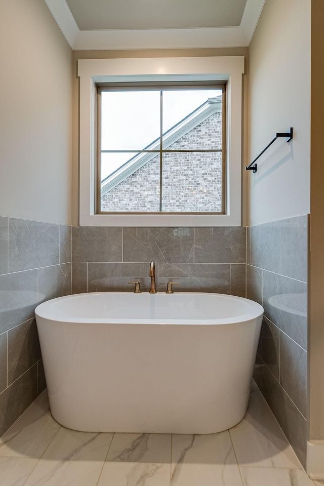 full bathroom featuring a healthy amount of sunlight, marble finish floor, and a soaking tub