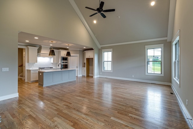 unfurnished living room featuring high vaulted ceiling, light wood-style floors, crown molding, and baseboards